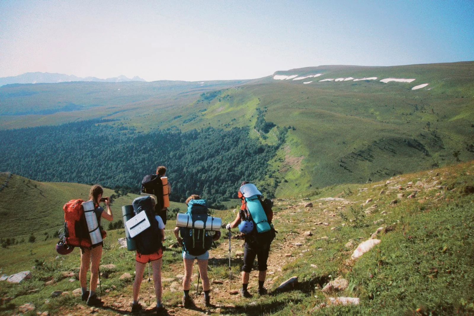 Group of outdoor enthusiasts hiking on a scenic mountain ridge trail overlooking peaks